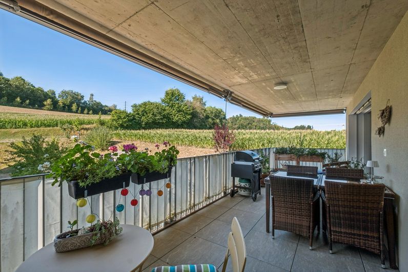 Gedeckter Balkon mit Sitzplatz und freiem Blick ins Grüne
