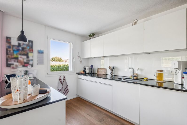 Moderne offene Küche mit weissen Fronten und dunkler Arbeitsfläche