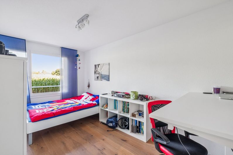 Helles Zimmer mit Holzboden, Fenster und Platz für Bett und Schreibtisch