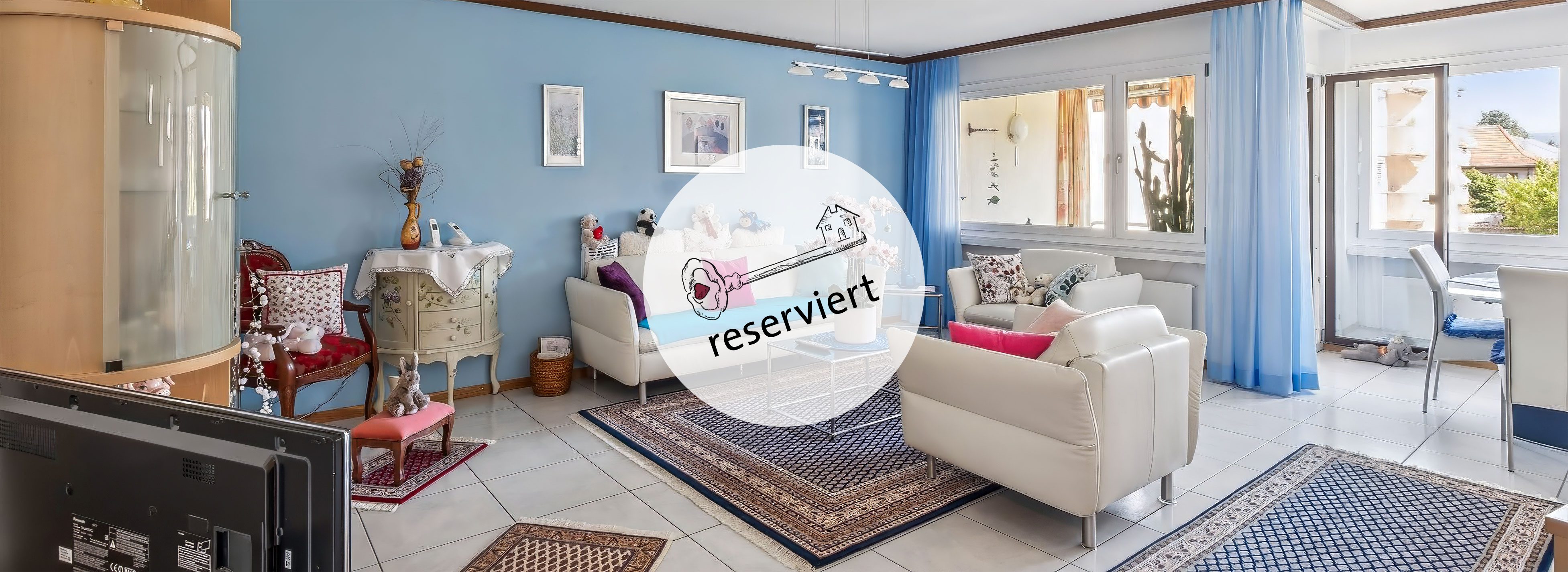 Helles Wohnzimmer einer 3,5-Zimmer-Wohnung in Langenthal mit blauen Wänden, weissen Ledersofas und Essbereich, reserviert.